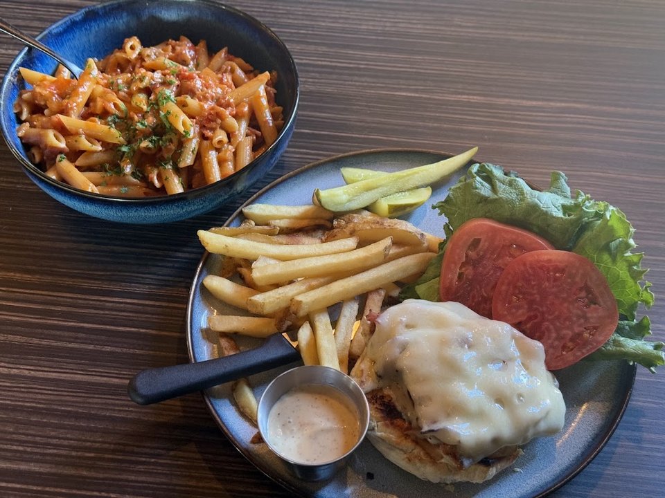 Plated pasta and sandwiches in warm light.